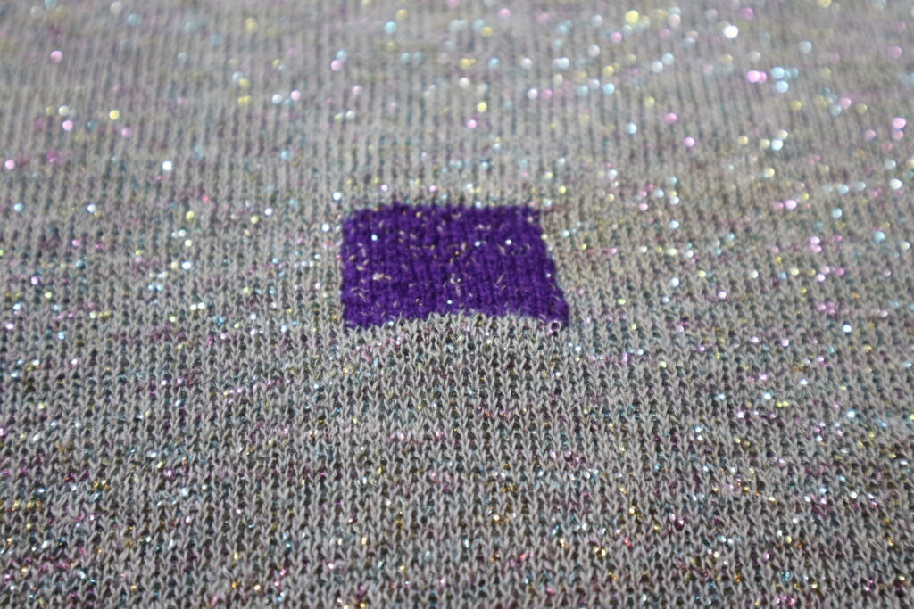 Visible mending: a purple square on a grey knitwear