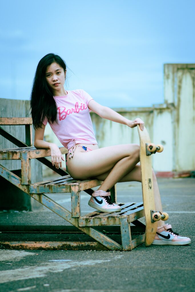 Girl wearing nike trainers and barbie t-shirt with skateboard